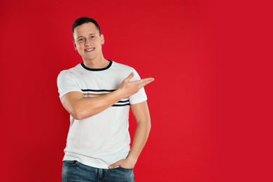 Photo of Happy handsome young man on red background. Space for text