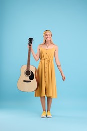 Happy hippie woman with guitar on light blue background