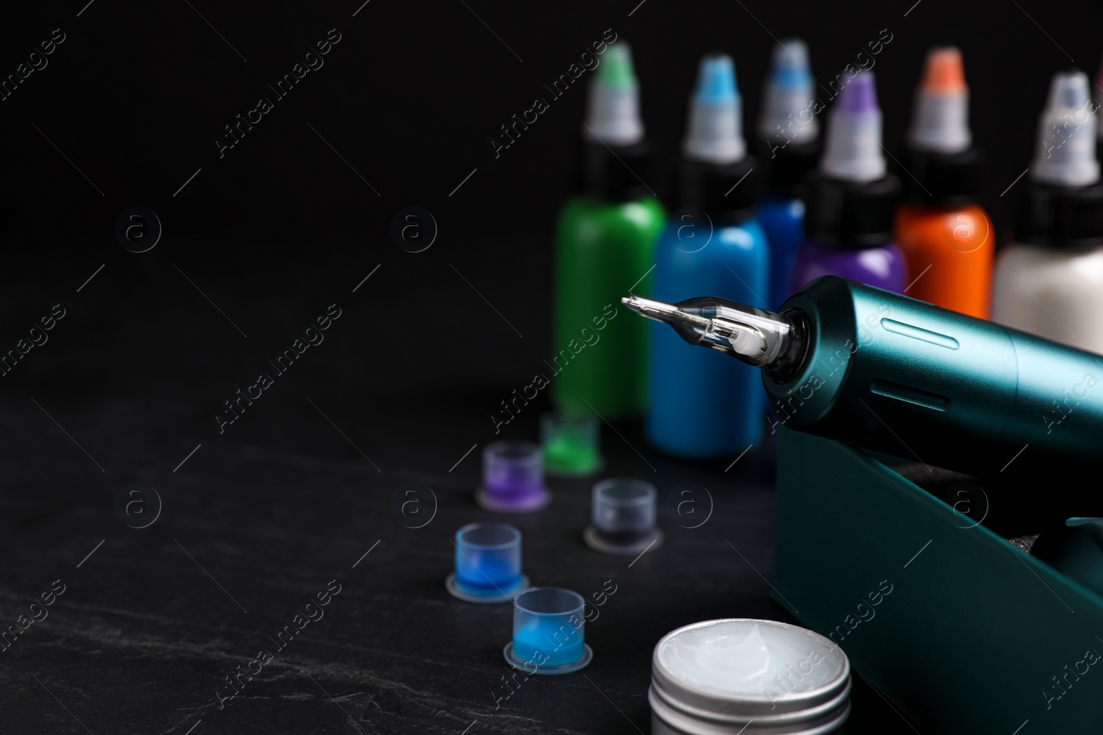 Photo of Tattoo equipment and machine in box on black table, closeup. Space for text