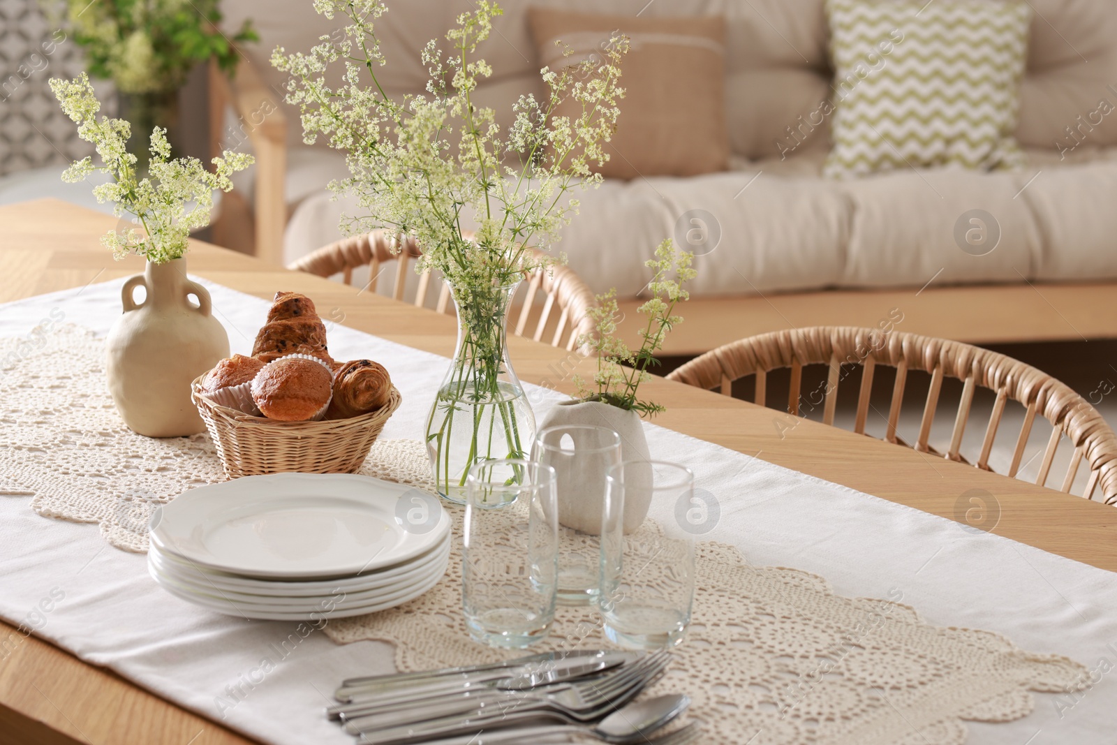 Photo of Clean dishes, flowers and fresh pastries on table in stylish dining room