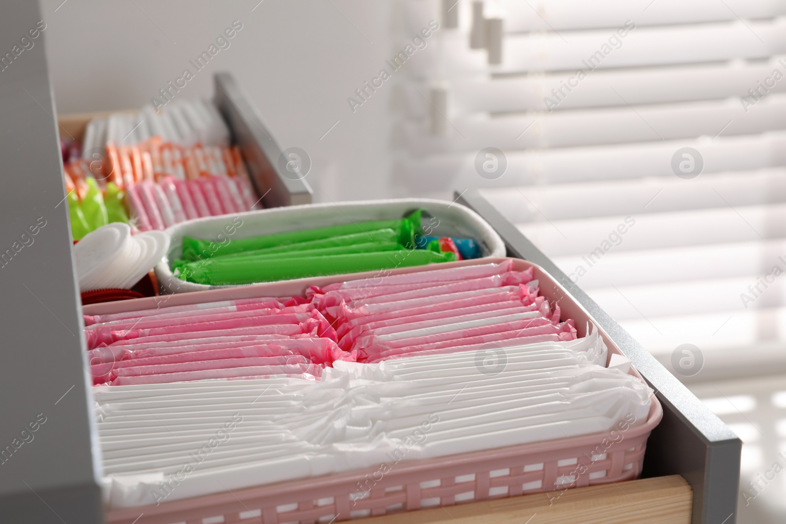 Photo of Open cabinet drawer with menstrual pads, tampons and pantyliners indoors, closeup