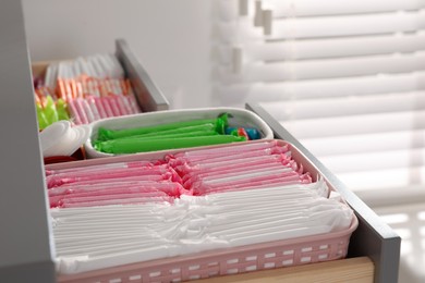 Photo of Open cabinet drawer with menstrual pads, tampons and pantyliners indoors, closeup