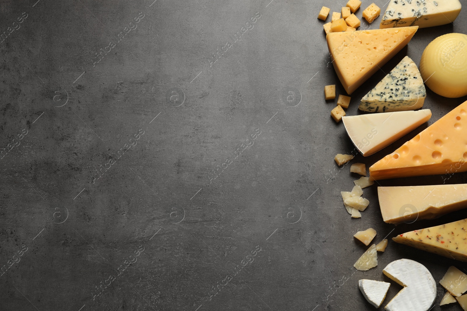 Photo of Different delicious cheeses on grey table, top view. Space for text