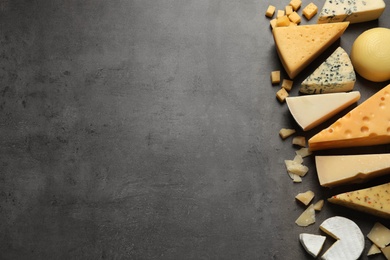 Photo of Different delicious cheeses on grey table, top view. Space for text