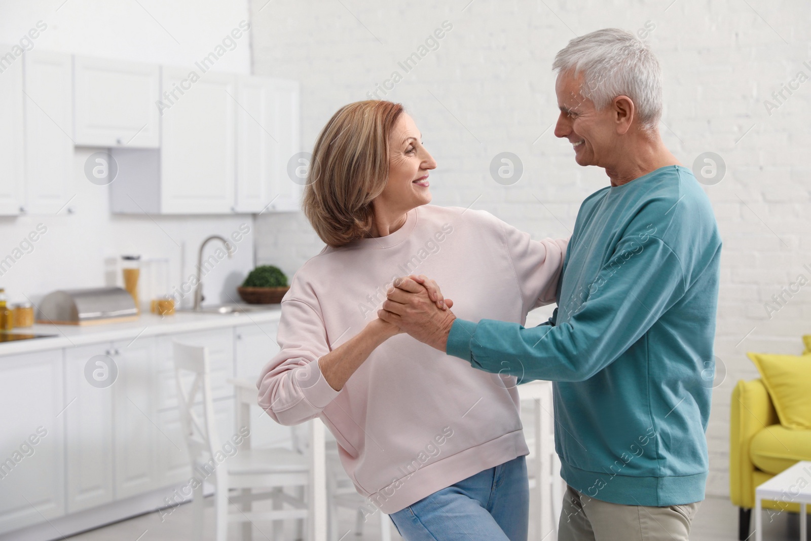 Photo of Happy senior couple dancing together in kitchen