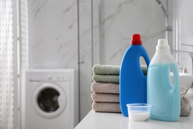 Photo of Stack of folded towels and detergents on white table in bathroom, space for text