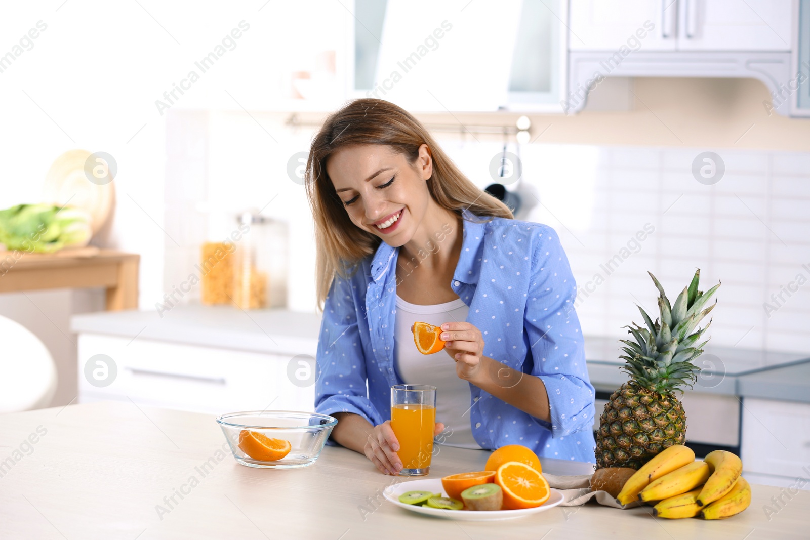 Photo of Woman making orange juice at table in kitchen. Healthy diet