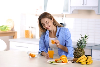 Woman making orange juice at table in kitchen. Healthy diet