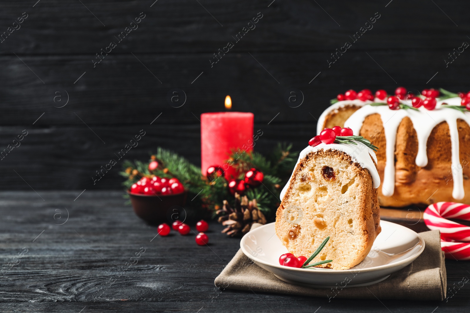 Photo of Composition with piece of traditional homemade Christmas cake on black wooden table. Space for text