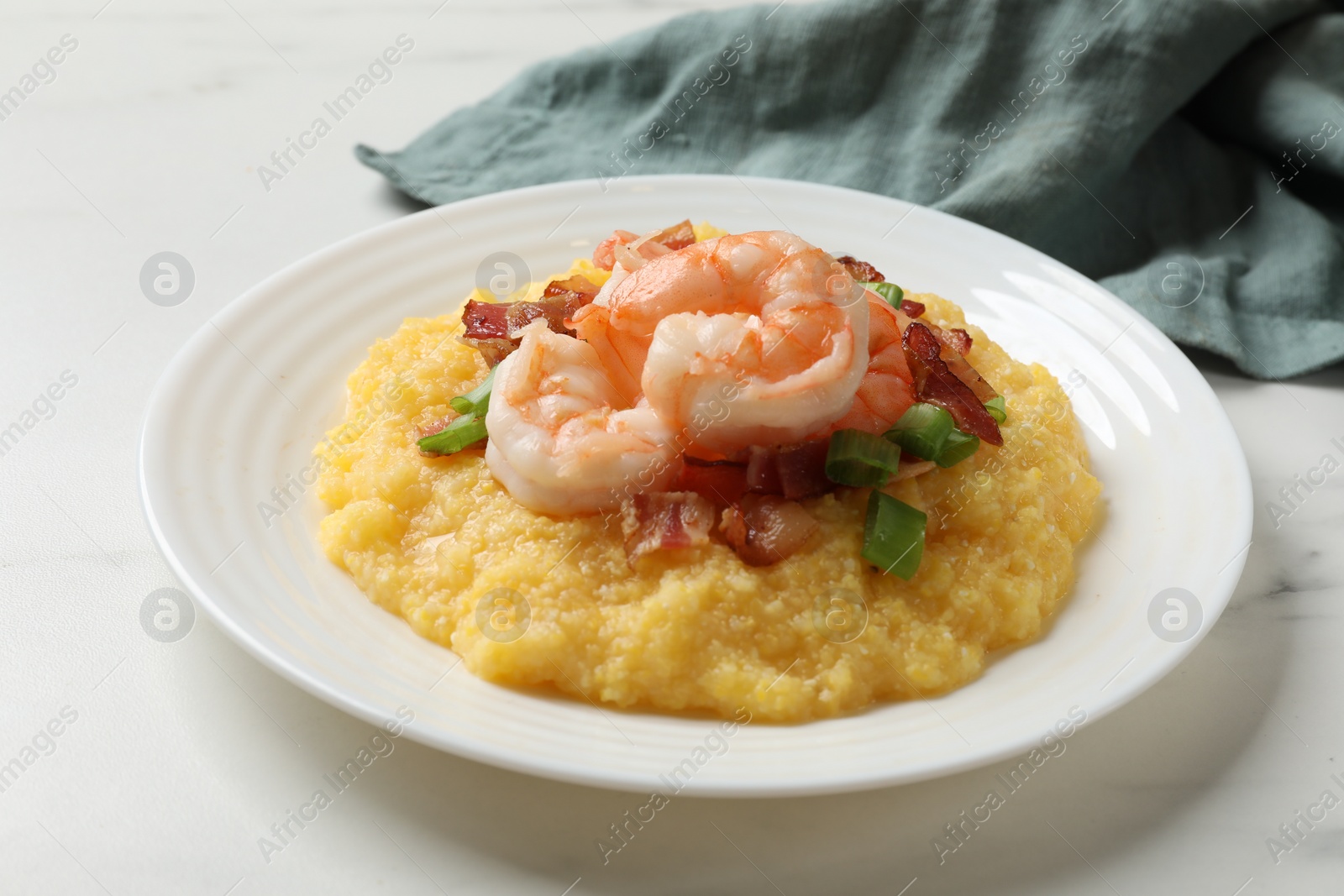 Photo of Plate with fresh tasty shrimps, bacon, grits and green onion on white marble table