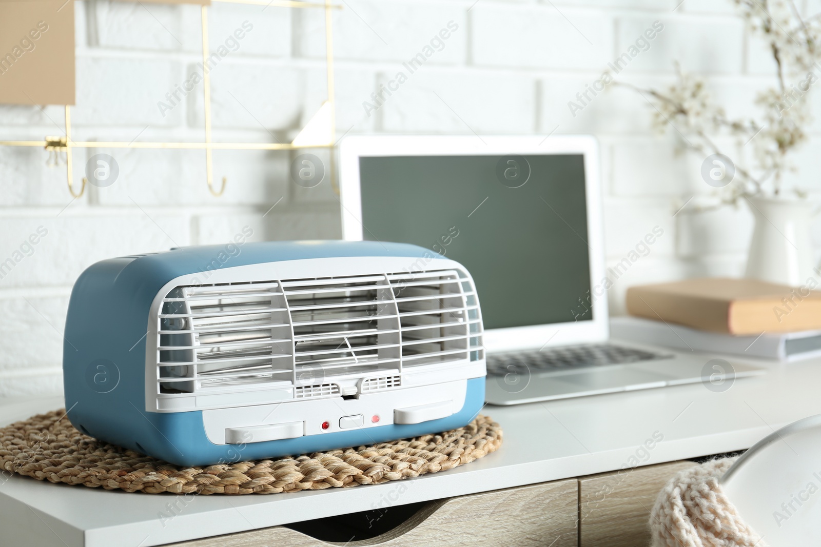 Photo of Modern air purifier near laptop on white wooden table in room