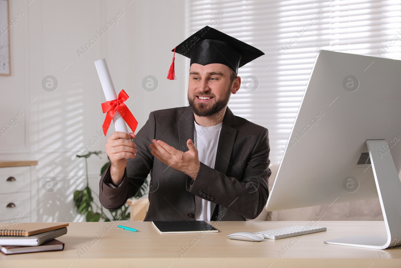 Photo of Happy student with graduation hat and diploma at workplace in office