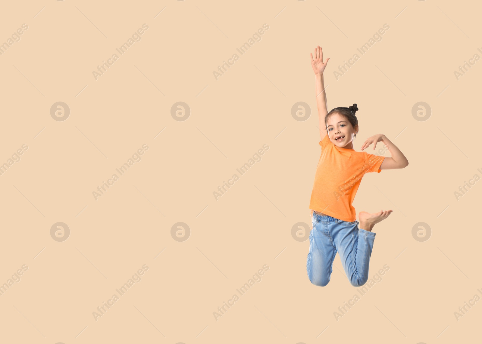 Image of Cute girl jumping on beige background, space for text