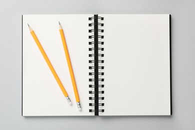 Notebook and pencils on gray background, top view