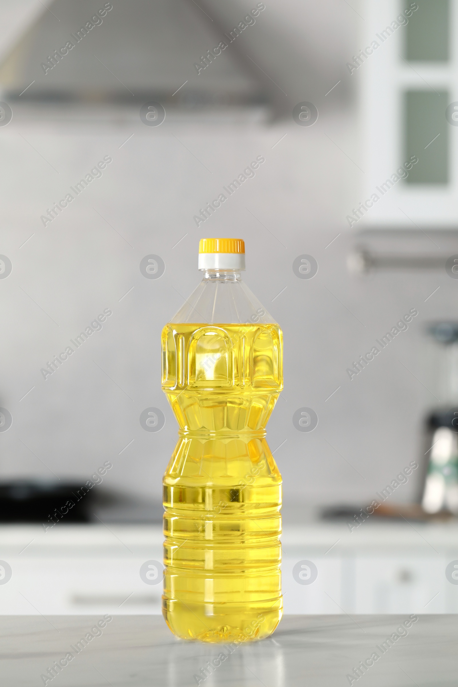 Photo of Bottle of cooking oil on white marble table in kitchen
