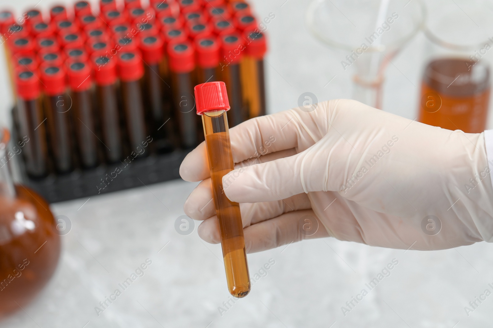 Photo of Scientist holding test tube with brown liquid, closeup