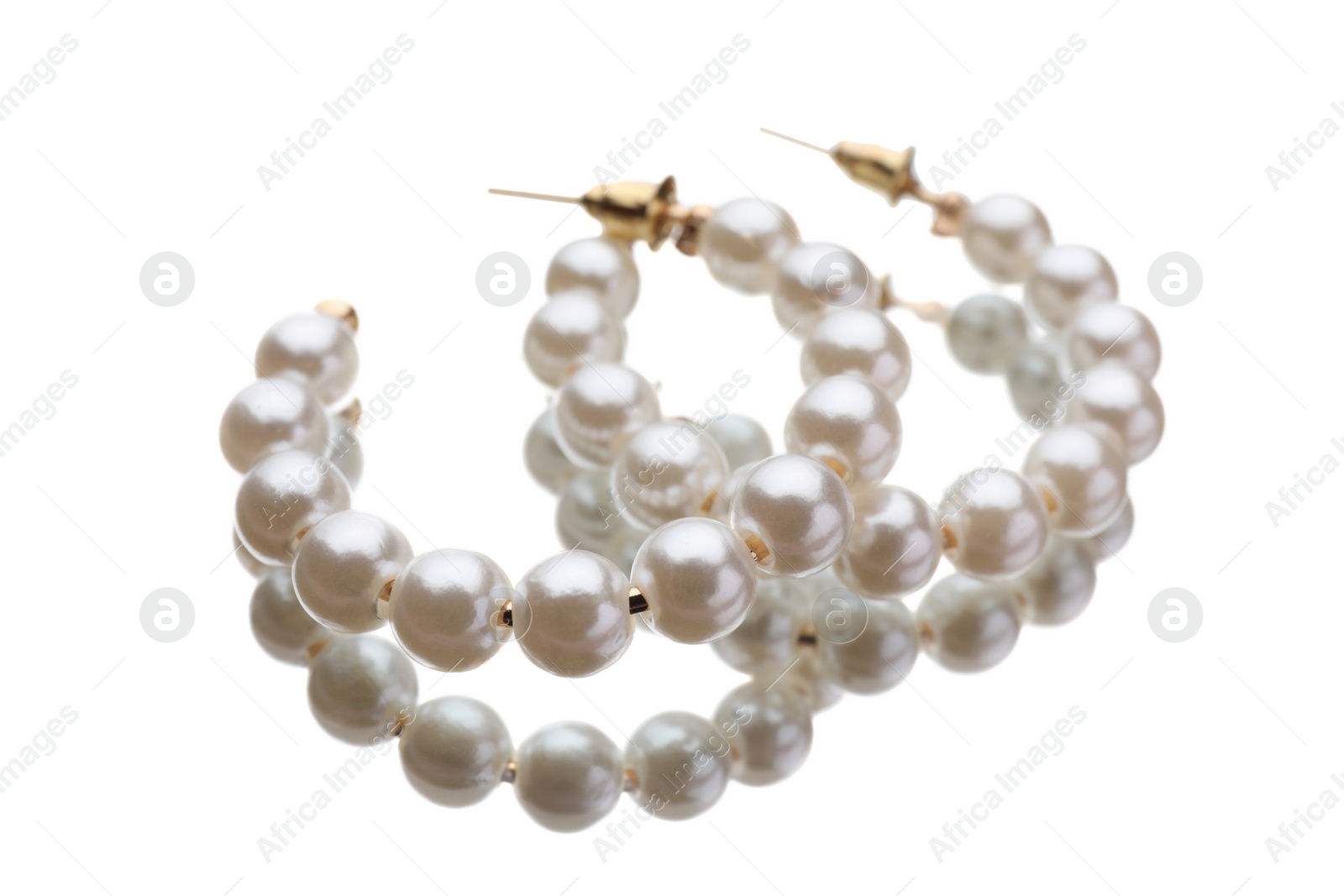 Photo of Elegant earrings with pearls on mirror surface