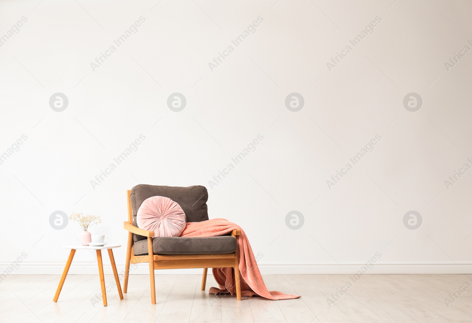 Photo of Stylish living room interior with comfortable armchair and wooden table near white wall. Space for text
