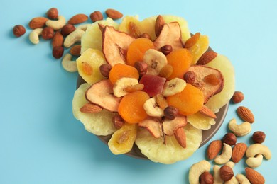 Photo of Mixed dried fruits and nuts on light blue background, closeup