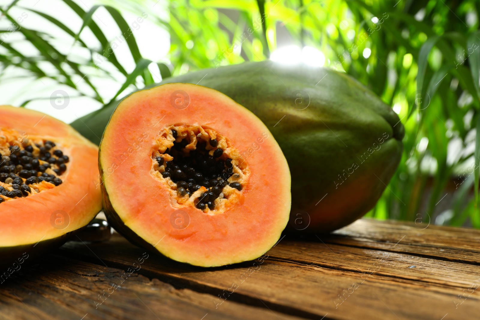 Photo of Fresh juicy ripe papayas on wooden table against blurred background, closeup view