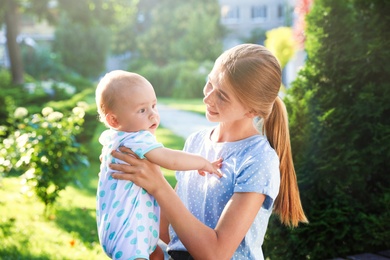 Teen nanny with cute baby outdoors on sunny day