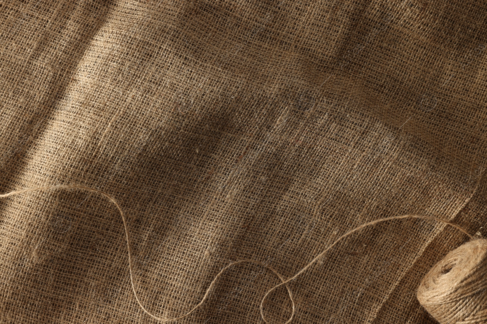 Photo of Spool of thread on burlap fabric, top view