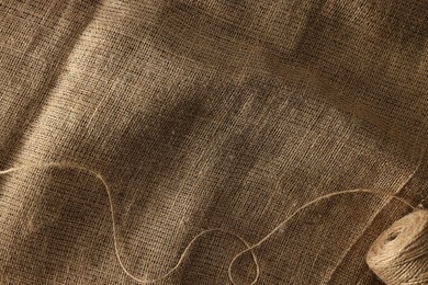 Spool of thread on burlap fabric, top view