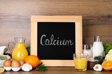 Photo of Food high in calcium. Different products and small chalkboard on wooden table