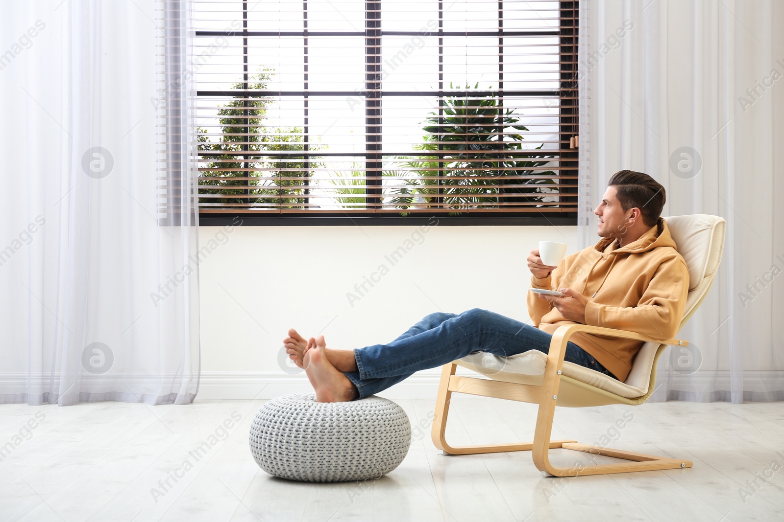 Photo of Attractive man relaxing in armchair near window at home. Space for text