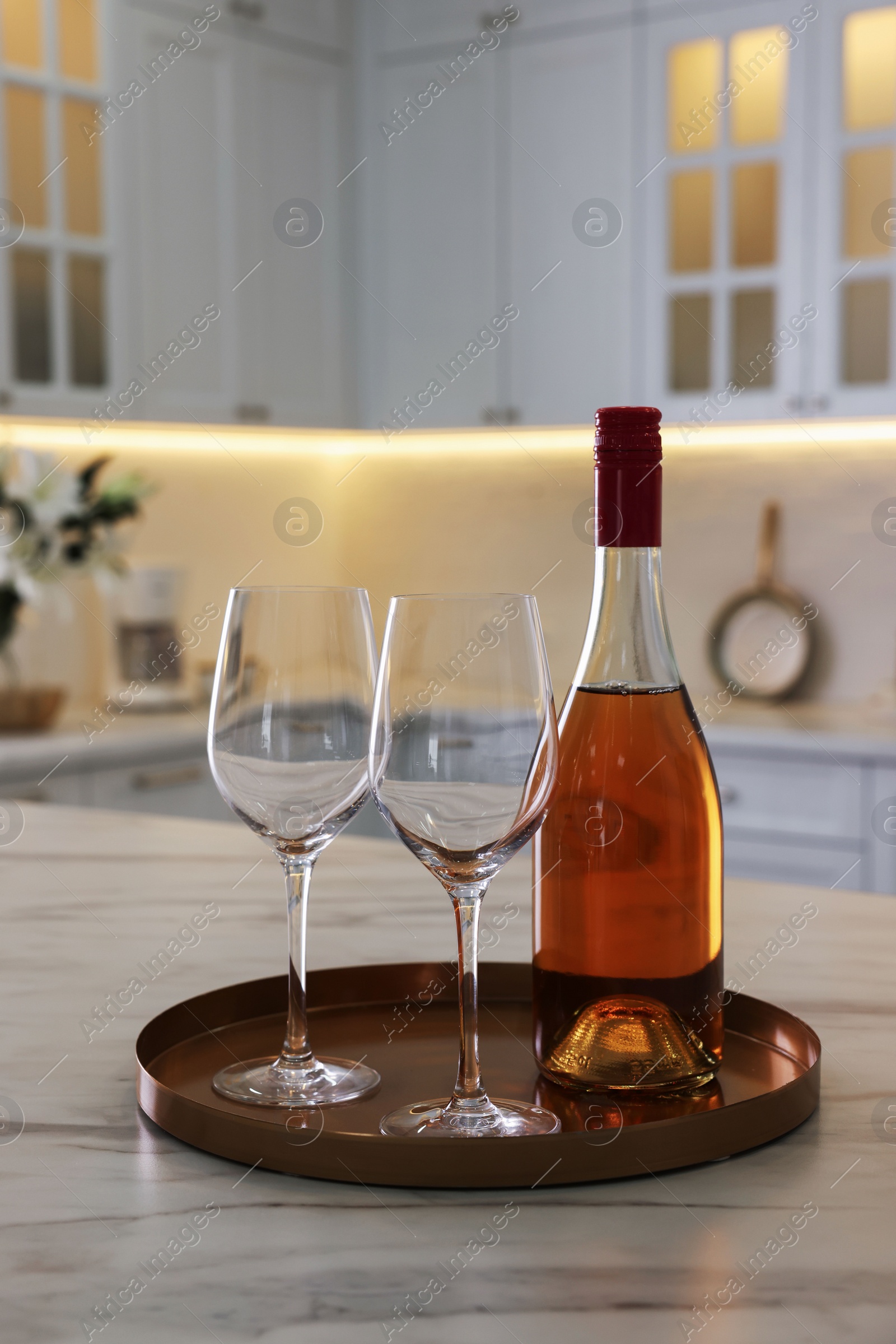 Photo of Bottle and glasses on white marble table in kitchen. Luxury interior