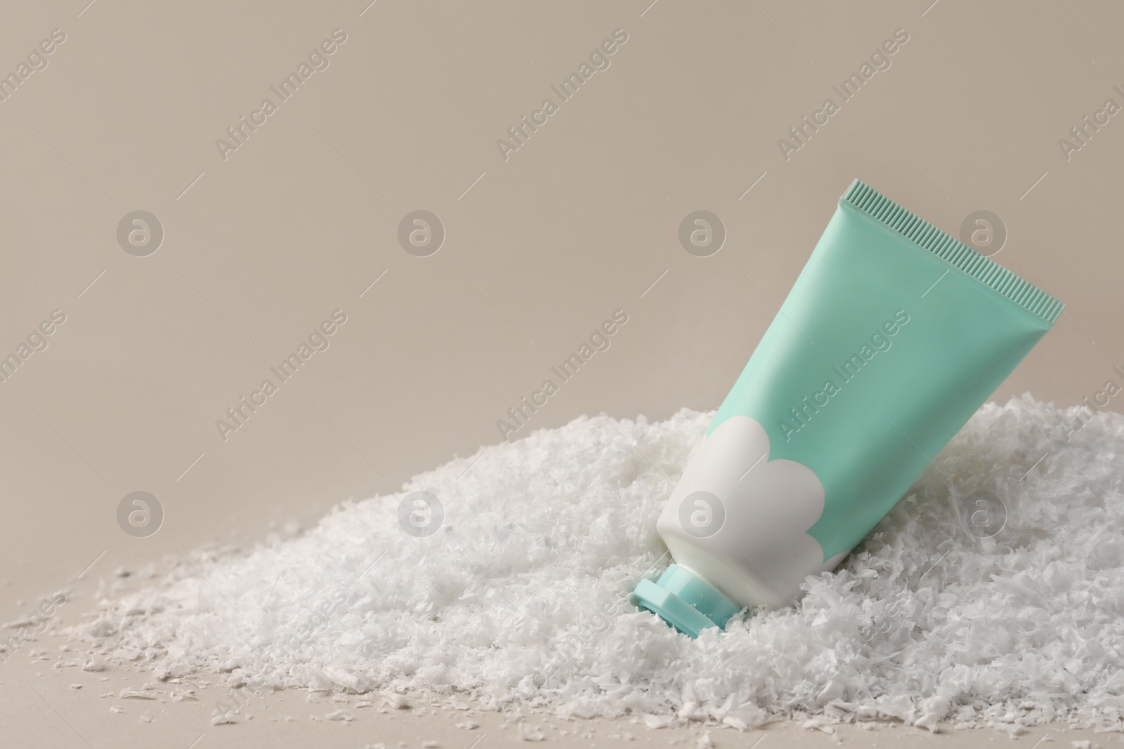 Winter skin care. Hand cream on artificial snow against light grey background, space for text Photo of Winter skin care. Hand cream on artificial snow against light grey background, space for text