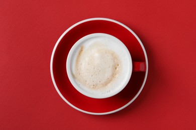 Cup with aromatic cappuccino on red background, top view