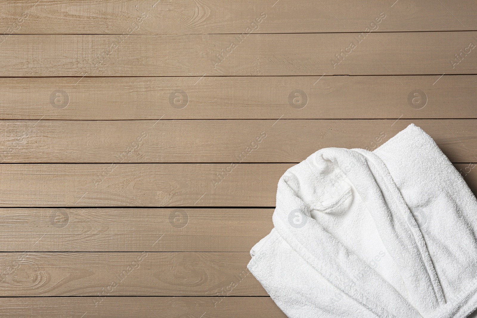 Photo of Clean folded bathrobe on wooden background, top view. Space for text