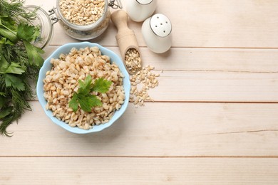 Photo of Delicious pearl barley with parsley served on wooden table, flat lay. Space for text