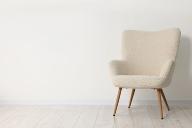 Comfortable armchair near white wall in room, space for text