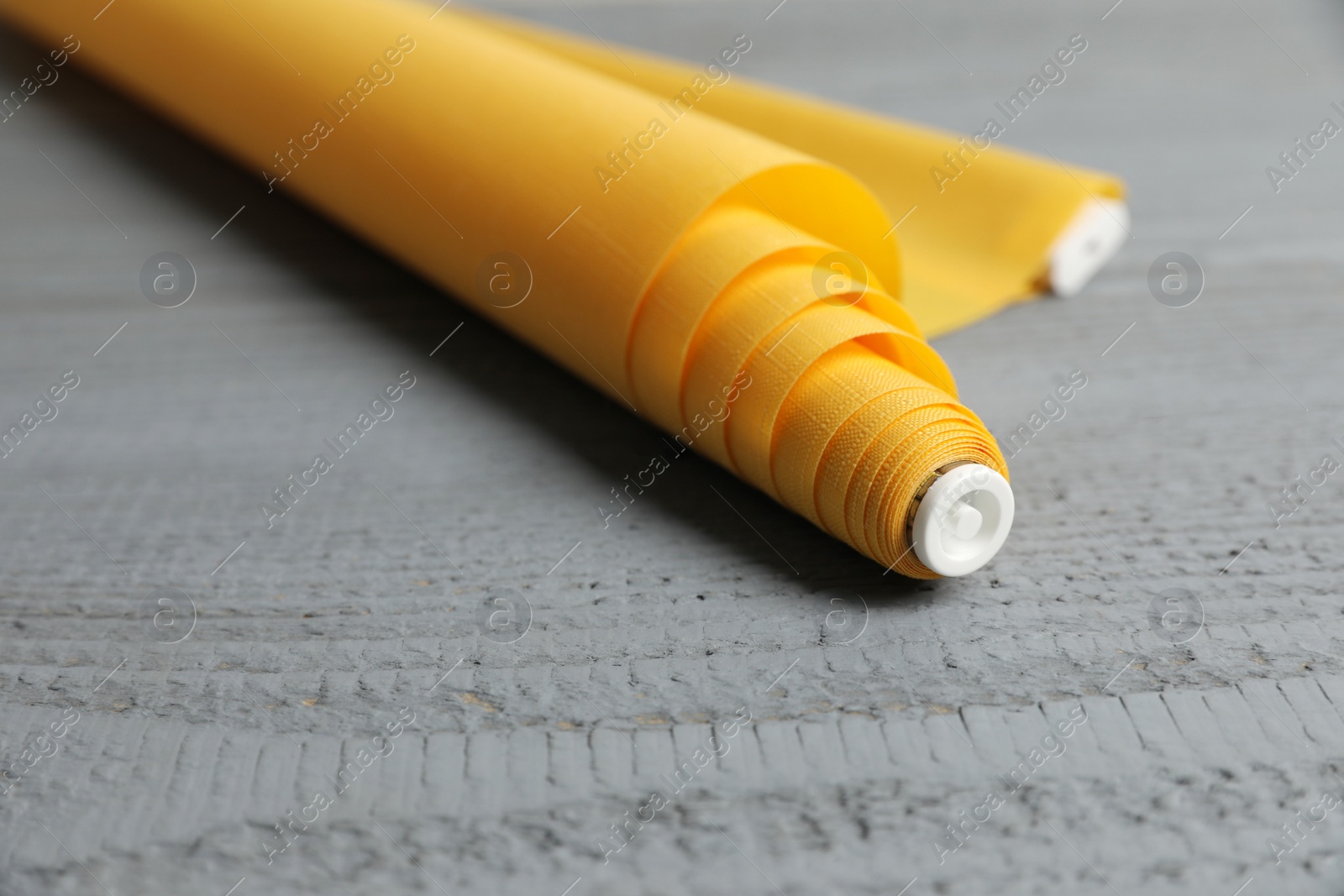 Photo of Stylish roller window blinds on grey wooden table