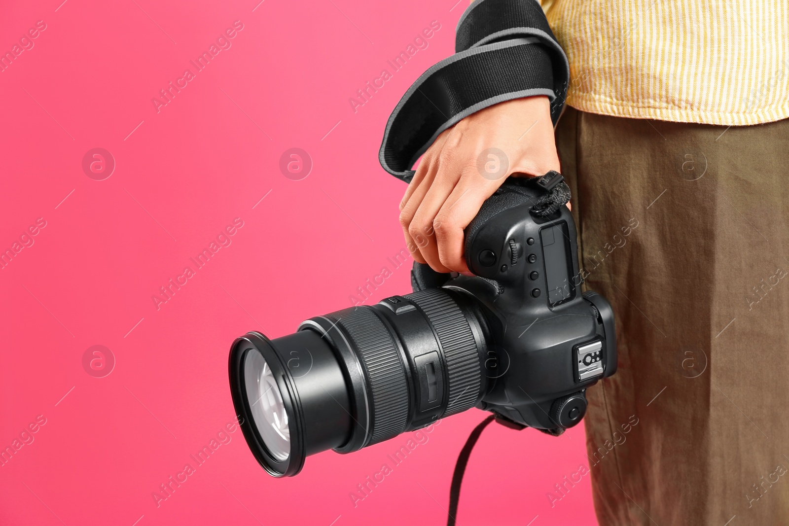 Photo of Professional photographer with modern camera on pink background in studio, closeup. Space for text