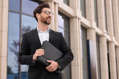 Photo of Real estate agent with leather portfolio outdoors. Space for text