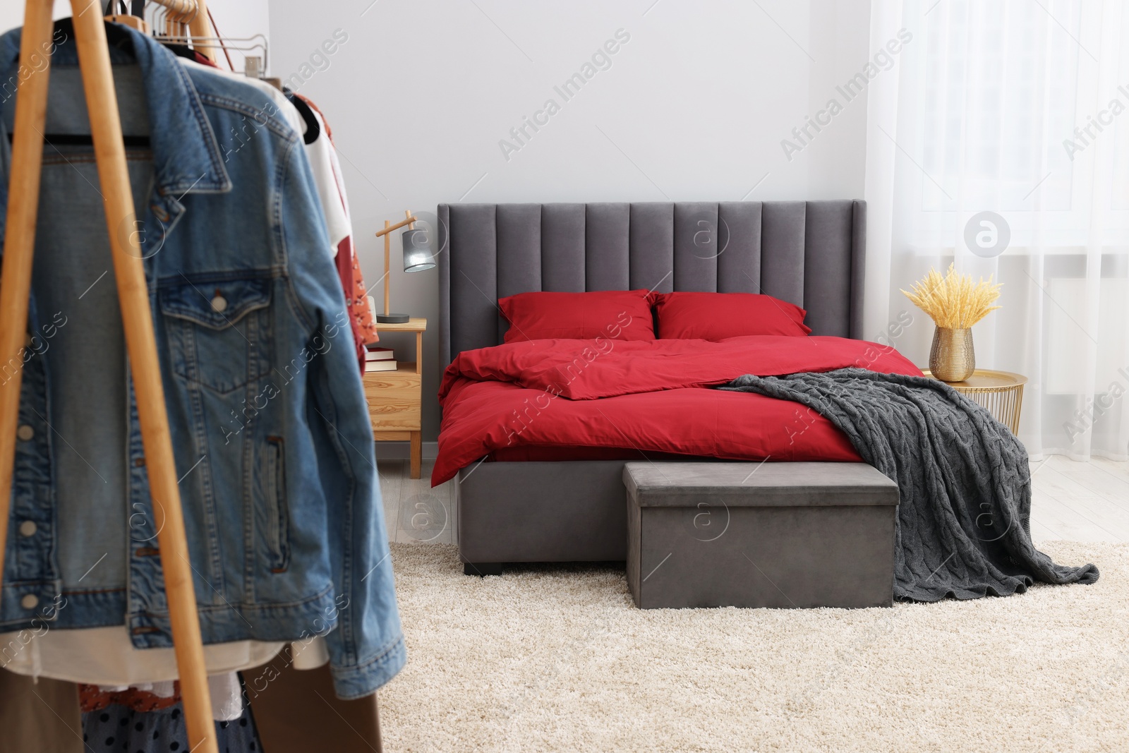 Photo of Stylish bedroom with comfortable bed and clothing rack. Interior design