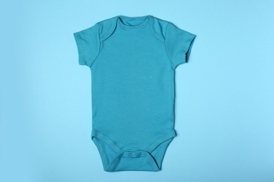 Photo of Cute baby onesie on color background, top view