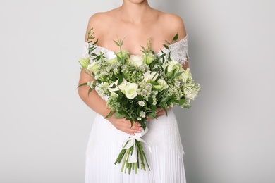 Photo of Young bride wearing wedding dress with beautiful bouquet on light grey background, closeup