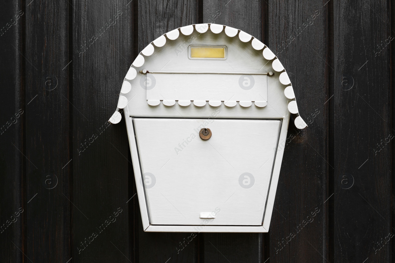 Photo of White metal letter box on wooden door outdoors