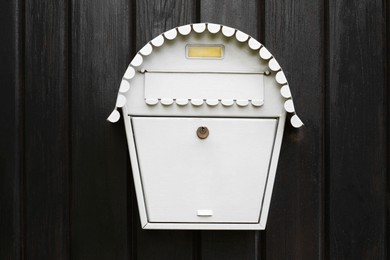 Photo of White metal letter box on wooden door outdoors