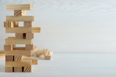 Photo of Jenga tower made of wooden blocks on white table, space for text