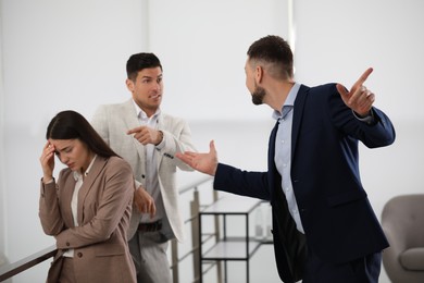 Photo of Boss scolding his employees in modern office
