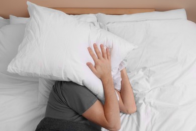 Photo of Man covering his face with pillow in bed, above view