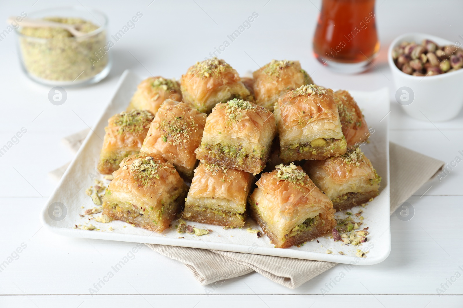 Photo of Delicious fresh baklava with chopped nuts on white wooden table. Eastern sweets