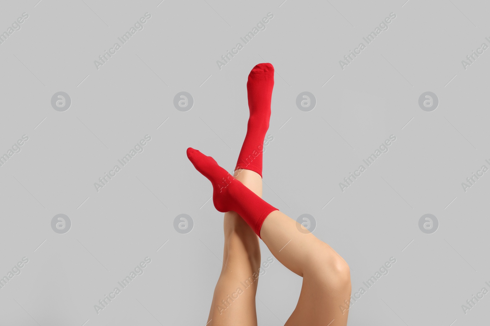 Photo of Woman in stylish red socks on light grey background, closeup