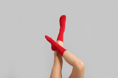 Photo of Woman in stylish red socks on light grey background, closeup