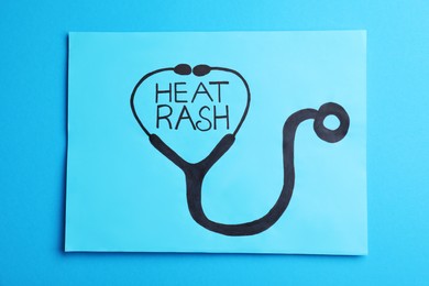 Photo of Words Heat Rash and stethoscope drawn on light blue background, top view